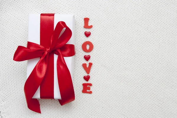 Caixa de presente branco com um arco vermelho e a palavra Amor flat lay on a wh — Fotografia de Stock