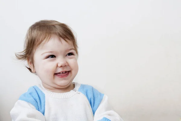 Забавная маленькая девочка со смехом с открытым ртом на белой спине — стоковое фото
