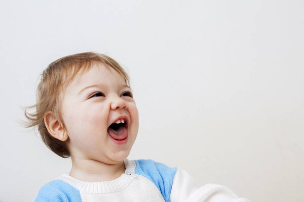 Cute little baby laughing a lot with open mouth on a white backg