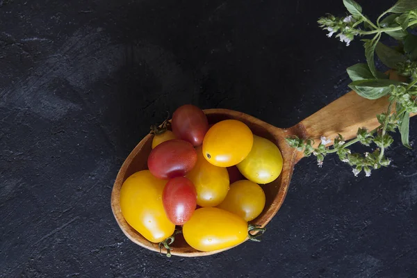 Tahta kaşıkta mini domatesler ve koyu renkli fesleğenler. — Stok fotoğraf