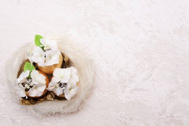 Yuvasında çiçekli, dokulu bir arka plan olan altın paskalya yumurtaları. Boşluğu kopyala