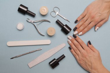 Mavi arka planda siyah beyaz manikür ve aksesuarlar.