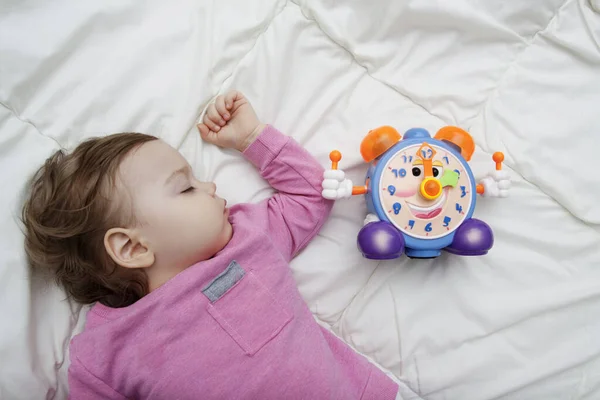 Uyuyan bir bebeğin yanındaki çalar saat. Her gün bebek sağlıklı uyku konsepti.