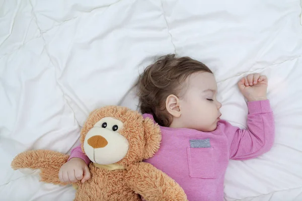 The baby sleeps with a toy bear. Healthy sleep baby concept.