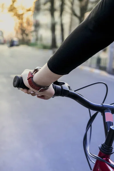 Female hand on the handlebars of a bicycle at sunset on the street. Modern sports lifestyle