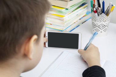 Masaüstünde akıllı telefonu olan ve ders alan bir okul çocuğunun elleri. Coronavirus Karantina Mesafesi Öğrenme Kavramı