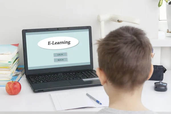 A boy with a laptop at a desk on distance learning. Quarantine Coronavirus Home Learning Concept