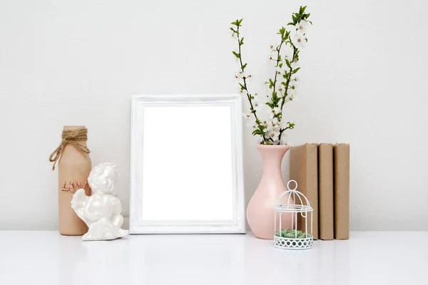 Empty white frame with a vase and books on the table. Spring mock-up for your text.