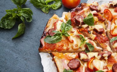 Sosisli, sebzeli ve peynirli pizza dilimlere bölünmüş.