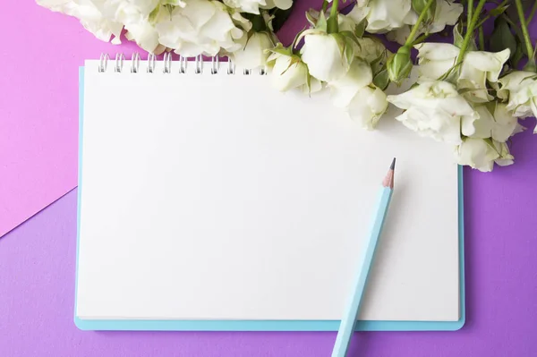 Prázdný poznámkový blok, tužka a květiny na růžovo-fialovém pozadí. Kopírovat místo pro text — Stock fotografie