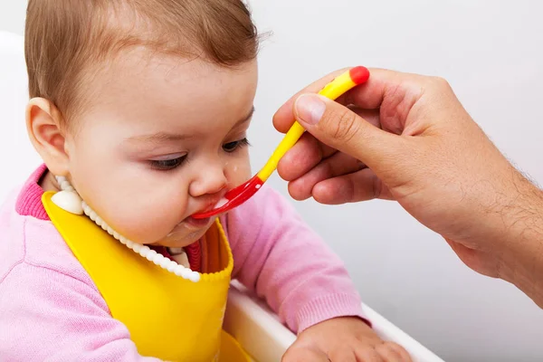 A baba etetés közben kinyitja a száját. Az apák egy szilikon kanálból etetik a babát. — Stock Fotó