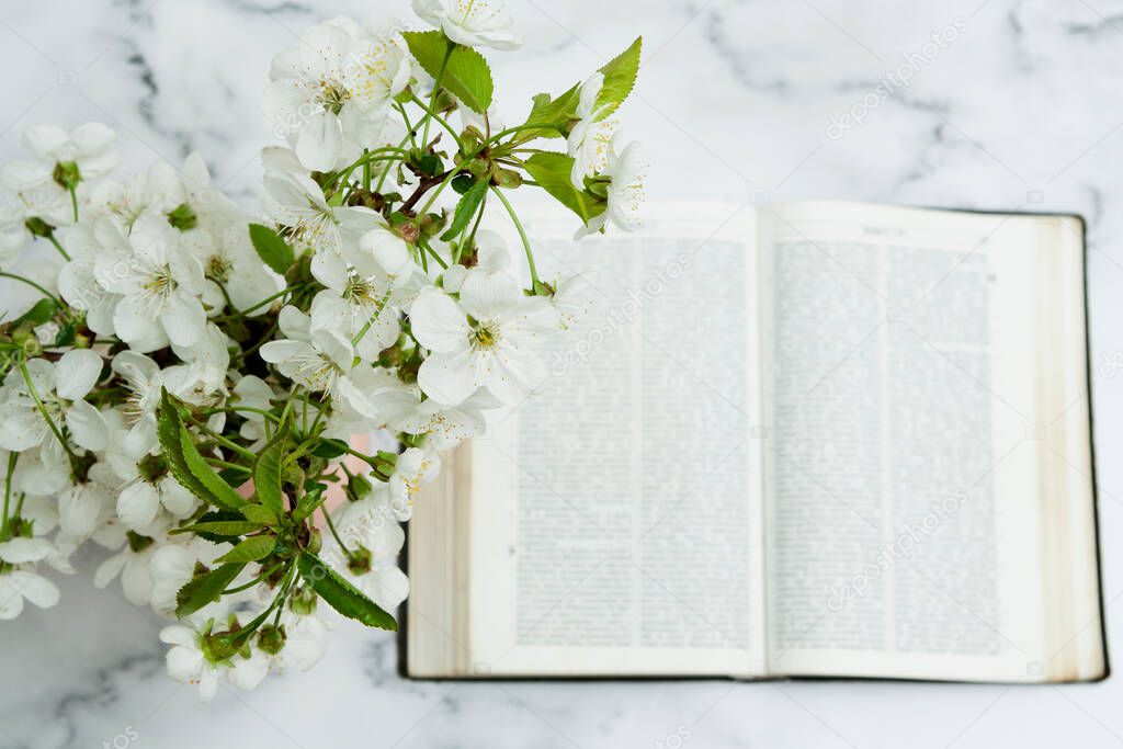 Flowers in a vase and an open Bible flat lay on the table