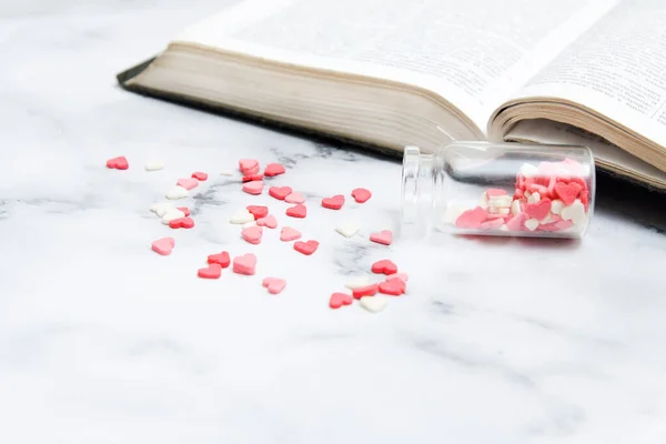 Hearts poured out of a bottle near an open bible. Bible as a source of love concept photo