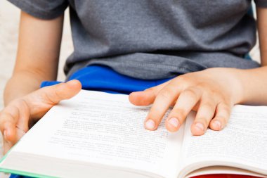 Bir çocuğun elleri bir kitabın sayfalarında. Çocuk kitap okuyor.