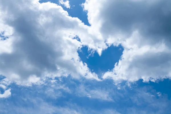 Herzform aus weißgrauen Wolken vor blauem Himmel — Stockfoto