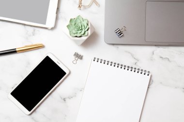 Çalışma alanının üst görüntüsü, bir defter maketi ve mermer arka planda aletler. İş masaüstü konsepti