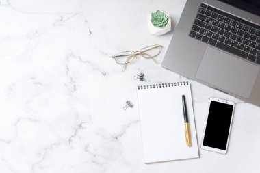 Üst görünüm çalışma alanı, defter, akıllı telefon, mermer arka planda fotokopi alanı olan dizüstü bilgisayar. İş masaüstü konsepti