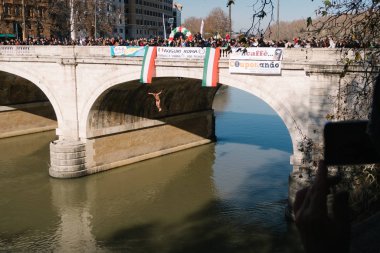 Rome, Italy - Jan 1, 2020: Athlet dives into the Tiber River from the 18 meter (59 feet) high Cavour Bridge in Rome