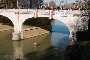 Rome, Italy - Jan 1, 2020: Athlet dives into the Tiber River from the 18 meter (59 feet) high Cavour Bridge in Rome