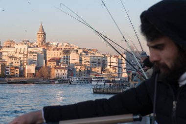 İstanbul, Türkiye - 10 Ocak 2020: Galata Köprüsü 'ndeki balıkçılar, Eminonu, Galata Köprüsü' nün arka planında yer alıyor. Türkiye