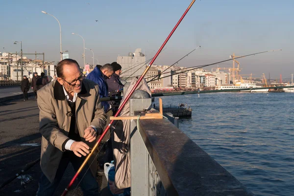 İstanbul, Türkiye - 10 Ocak 2020: Galata Köprüsü 'nde Beyoğlu' nun arka planındaki Eminonu ilçesinde balıkçılar. Türkiye