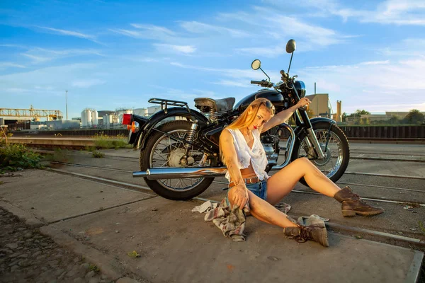 Seksi kadın gün batımında kırık motosikleti tamir ediyor.. — Stok fotoğraf
