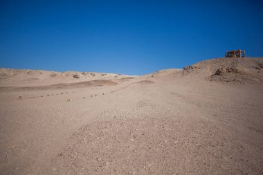 Mavi gökyüzü arka plan üzerinde çölde taşlarla işaretlenmiş asfaltsız yol
