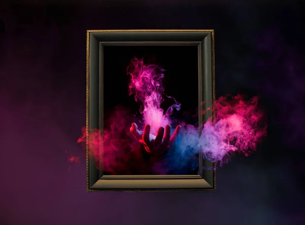 colorful smoke with hand reaching out from wooden frame