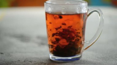 Renkli arka planda cam bardakta demlenmiş amber çiçekli doğal Seylan siyah çay yığını.