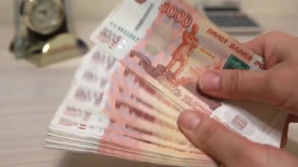 Russian money is laid out like a fan in his hand and placed it on the table — Stock Video