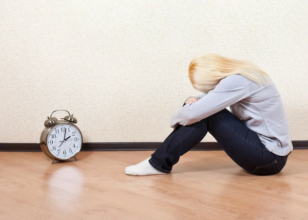 Gadis sedih duduk di lantai sebelah jam besar — Stok Foto