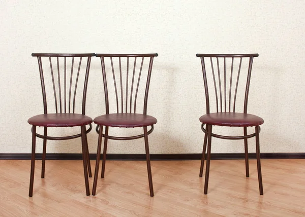 Drei desselben Stuhls gegen die Wand — Stockfoto
