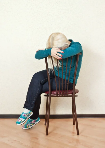Расстроенная блондинка спит сидя на стуле — стоковое фото