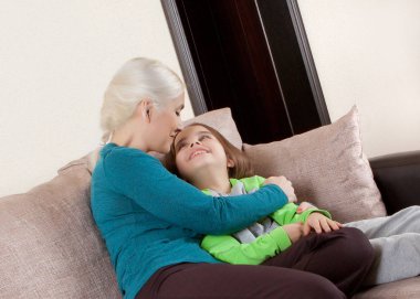 Mutlu anne ve kızı evde kanepede oturan