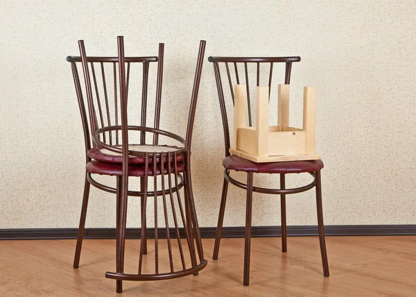 Three identical wooden chair and children's stool against the wall — Stock Photo, Image