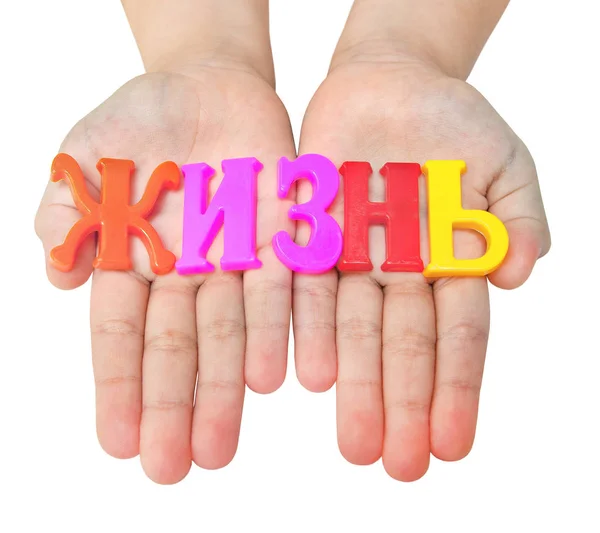 Слово "жизнь", выложенное цветными русскими буквами на детских руках — стоковое фото