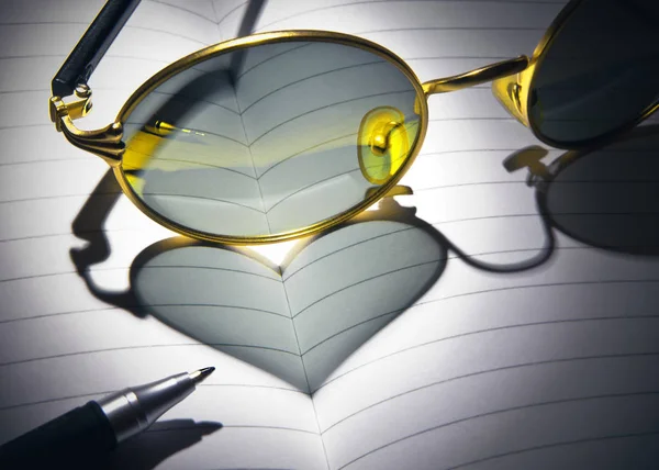 Gold-rimmed spectacles on the notebook with pen