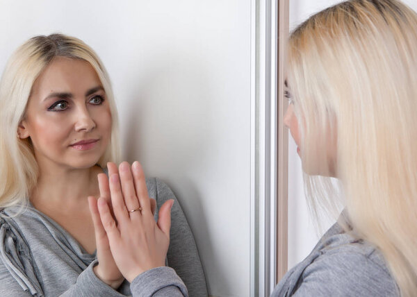 The woman talks to herself in the mirror.