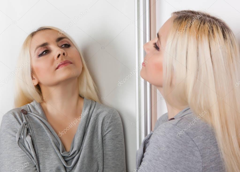 A woman stands in front of a mirror.