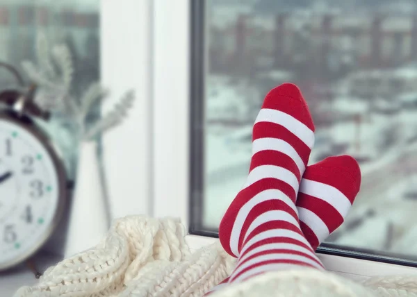 Ноги Полосатых Носках Ярко Прижаты Зимнему Окну Рядом Часами Вазой — стоковое фото