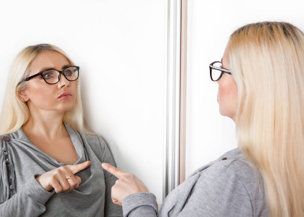 A woman pokes a finger at his reflection in the mirror.