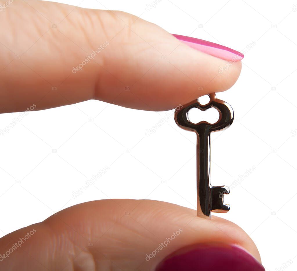 Small metal key between the fingers, isolated on a white background