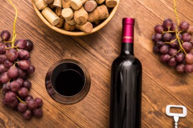 Bottles of wine, glasses of wine, grapes and cork wine on a wooden background. clipart