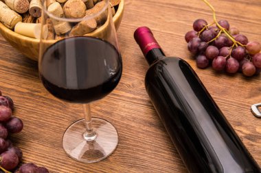 Şarap, kadeh şarap, üzüm ve ahşap arka plan üzerinde mantar şarap şişe.