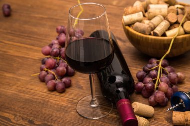 Şarap, kadeh şarap, üzüm ve ahşap arka plan üzerinde mantar şarap şişe.