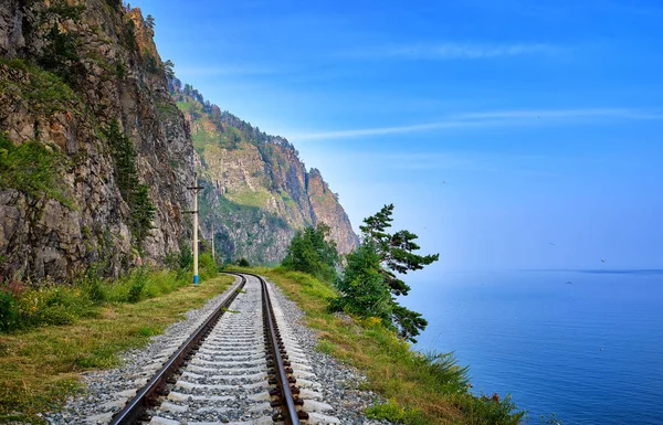 Línea de ferrocarril de vía única en el borde de la tierra entre la roca escarpada y el lago Baikal —  Fotos de Stock