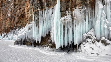 Uzun buz sarkıtları kayanın üzerine. Deniz Baykal