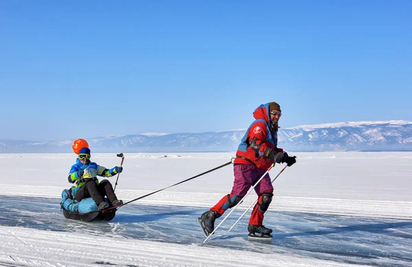 贝加尔湖, 伊尔库茨克地区, 俄罗斯-2017年3月08日: 满意的人是滚动的女人坐在雪橇拖 — 图库照片