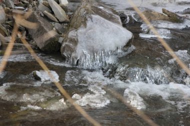 Basamaklı bir su yolu kış sezonu başında banka yakınındaki kayalarda şekillendirme buz.  