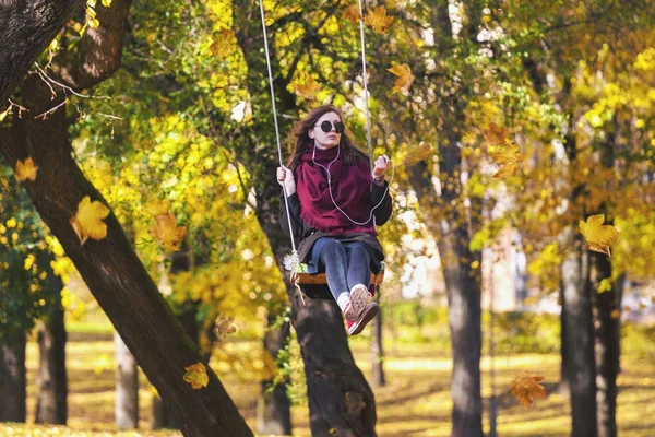 Mladá dospělá žena houpání na houpačce v podzimní park — Stock fotografie